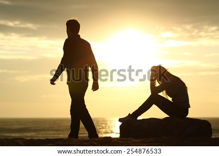 Couple silhouette breaking up a relation on the beach at sunset Royalty-Free Stock Photo #254876533