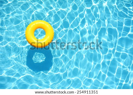 Yellow pool float, ring floating in a refreshing blue swimming pool Royalty-Free Stock Photo #254911351