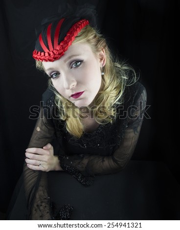 Young woman wearing red and black hat in black dress