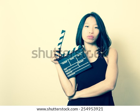 Young beautiful asian woman showing clapperboard and vintage colors portrait