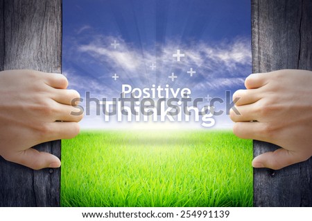 "Positive Thinking" Motivational quotes. Hands opening a wooden door then found a texts floating among new world as green grass field, Blue sky and the Sunrise.