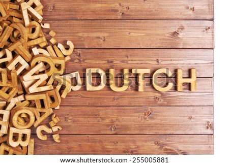 Word dutch made with block wooden letters next to a pile of other letters over the wooden board surface composition