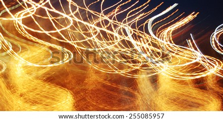 Lights in motion in the dark - vintage effect. Wavy light trails. Bright orange colors. Freezelight photo - retro filter. Wide photo for web page texture or site slider.