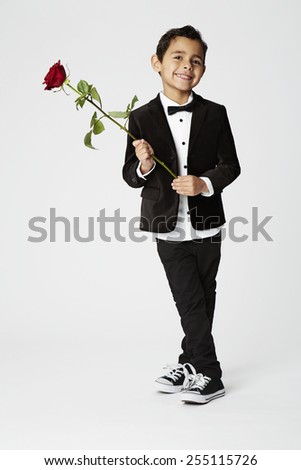 Young boy holding romantic red rose, studio