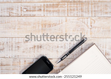 Notebook and phone on wood table for  background
