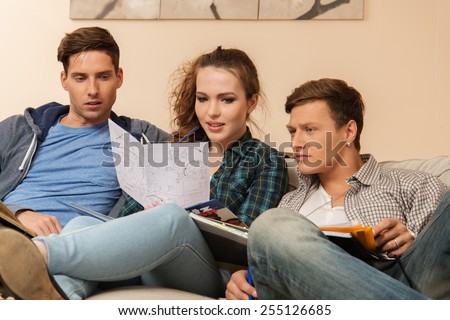 Three young students preparing for exams in apartment interior 