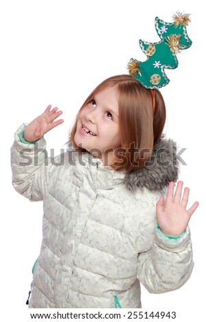 Studio image of a charming funny little girl in warm coat and with a crown on the head of a tree on a white background