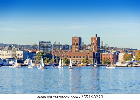 Harbour with boats and wooden yacht with town hall on background at sunset in Oslo, Norway Royalty-Free Stock Photo #255168229