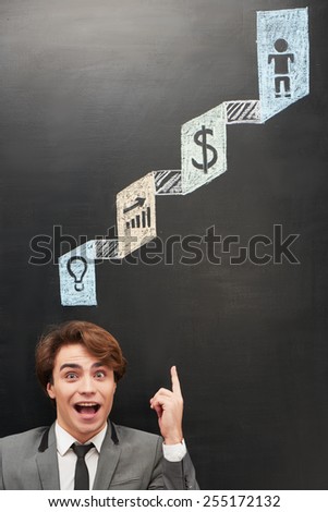 Casual cheerful man standing near dark chalkboard with colorful symbols painted on it