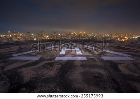 Helipad on the roof of a skyscraper at night with cityscape view