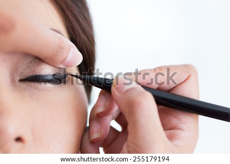 makeup beauty with brush eye liner on pretty woman face Royalty-Free Stock Photo #255179194