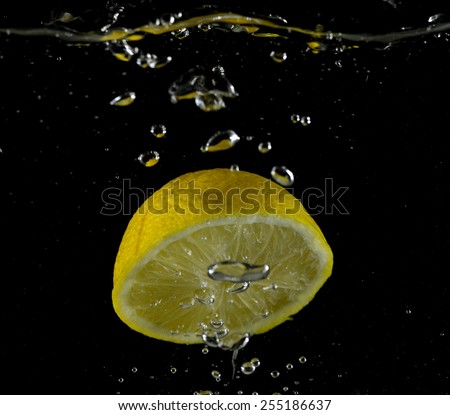 Lemon flying into the water, collision with lemon water (on a black background)