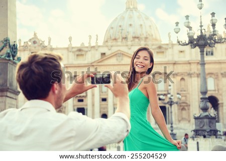 Couple taking smartphone picture at Vatican, Italy. Boyfriend using phone to take portrait pictures of girlfriend posing in front of the Basilica in Rome, Italy. Italian vacations travel.