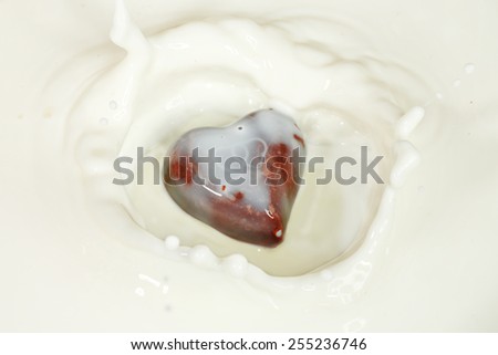 chocolate heart falling into milk surface