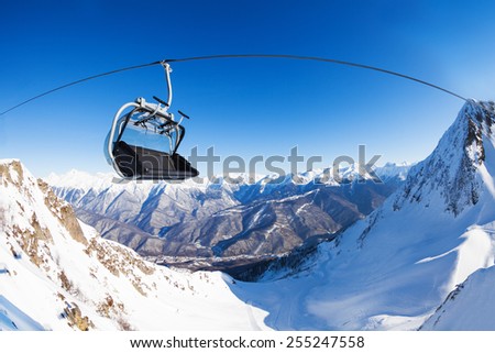 Chair on ski lift over mountain peaks panorama 