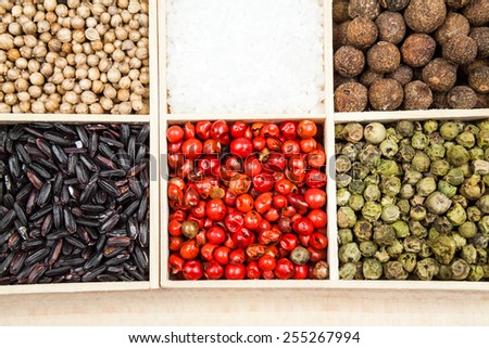 Spices and black rice in a wooden box: red, green and white pepper, sea salt, himalayan salt, allspice and coriander 