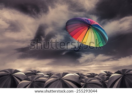 rainbow umbrella fly out the mass of black umbrellas Royalty-Free Stock Photo #255293044