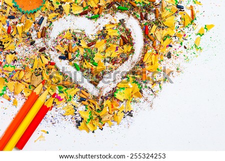 heart, multicolored pencils and varicolored wooden shavings on the white background