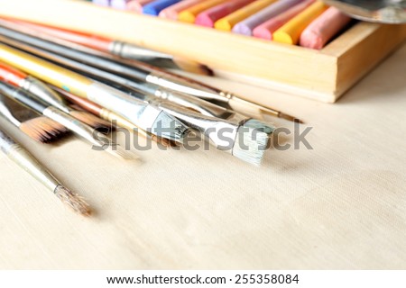 Paintbrushes with colorful chalk pastels in box on fabric background
