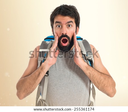 Backpacker doing surprise gesture over ocher background