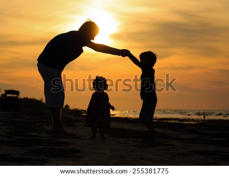 father and son making home for little daugther at sunset beach