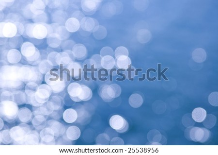 Out of focus bokeh background of blue water with sun reflections
