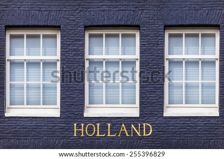 Windows of an Amsterdam canal house with the bronze letters "Holland" beneath it