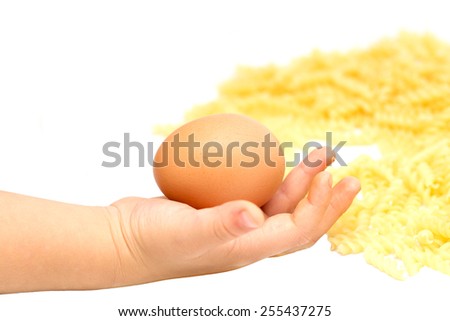child holding an egg next to the pasta on a white background