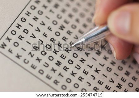 Woman's hand with ballpoint pen and wordsearch puzzle.
