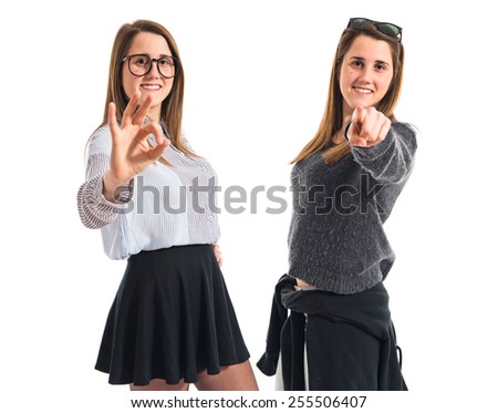 Twin sisters pointing to the front and doing OK gesture