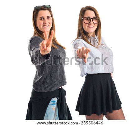 Twin sisters pointing to the front and doing victory gesture