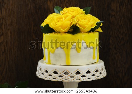 Homemade carrot cake decorated with yellow roses and glaze.