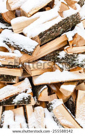 Stacked chopped firewood covered by snow
