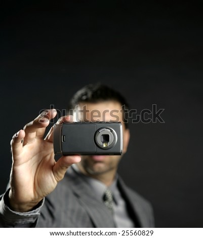 Businessman taking photos, mobile camera, black background