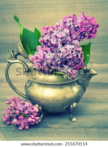 Lilac flowers bouquet on wooden background. Retro style toned picture