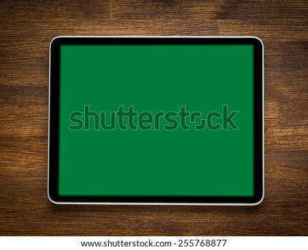 Blank modern digital tablet on a wooden desk. Top view. With isolated screen 