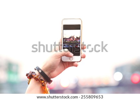 blurred people hand hold phone take photo in concert and travel up to sky with purple light background, internet and communication lifestyle.