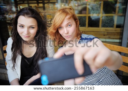 Two young girls taking a self portrait (selfie) with smart phone 