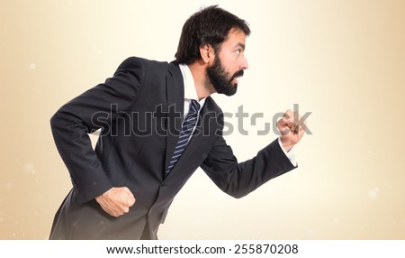 Businessman running fast over ocher background