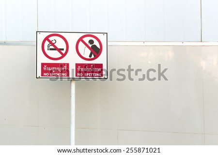 Public park white sign to prohibit smoking and spitting area with mixture of tile and metal sheet background