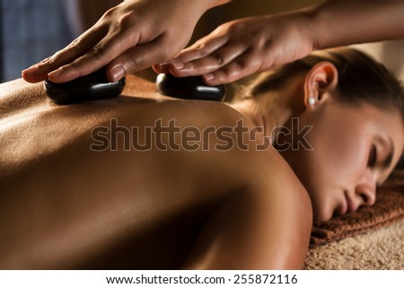Stone therapy. Massage with hot basalt stones. Focus on the hands Royalty-Free Stock Photo #255872116