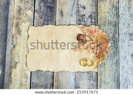 Close up gold ring, dry leaves and old paper on wooden background