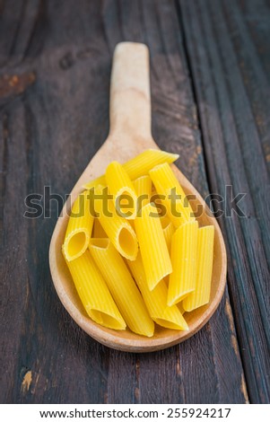 Raw pasta on spoon on wooden background - process old style pictures