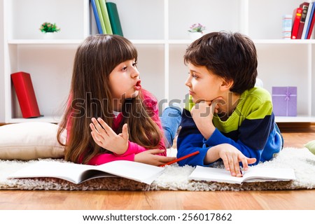 Little girl and little boy have decided to take a break from homework and now they are having conversation.Children talking Royalty-Free Stock Photo #256017862