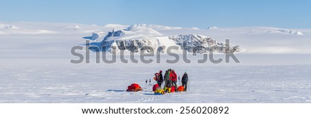 a group of people on winter expedition on ski with sled in wilderness mountainous landscape - panoramic view