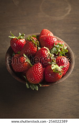 Strawberries in a bowl with wooden background