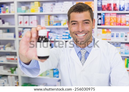 Handsome pharmacist showing medicine bottle at the hospital pharmacy