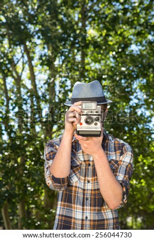 Handsome hipster using vintage camera on a summers day