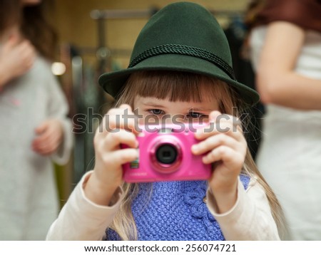 Pretty little photographer taking a picture in doors