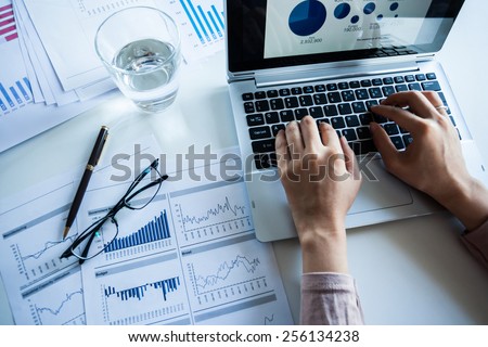 Businessman checking reported profits on the paper and laptop. Royalty-Free Stock Photo #256134238